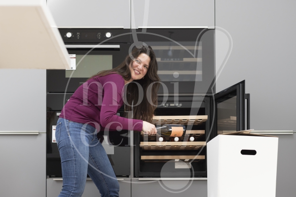Vrouw legt wijnflessen in de koelkast 2