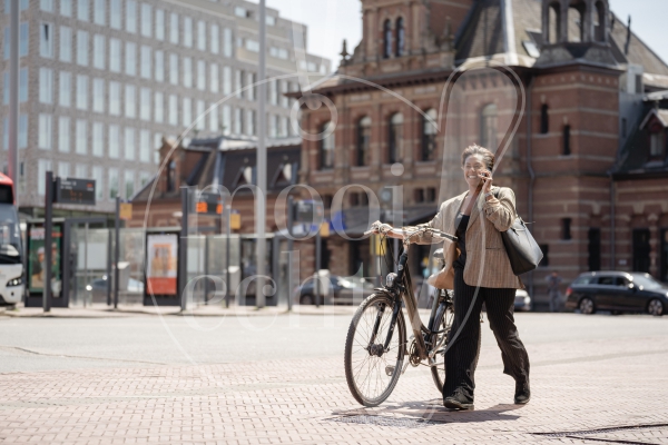 Vrouw loopt met fiets over stationsplein 1