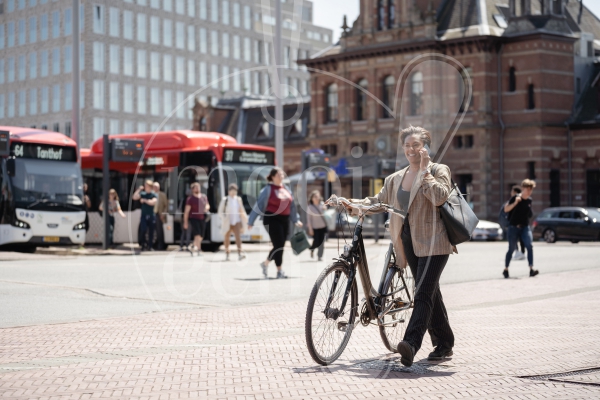 Vrouw loopt met fiets over stationsplein 3